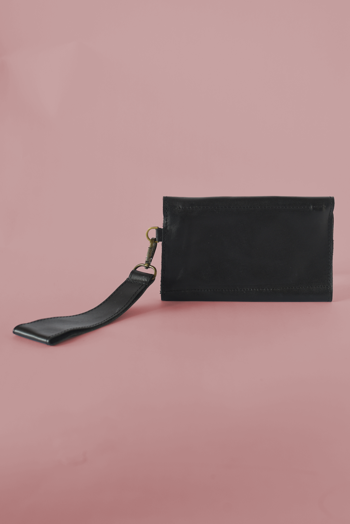 Black leather pouch with strap on a pink background
